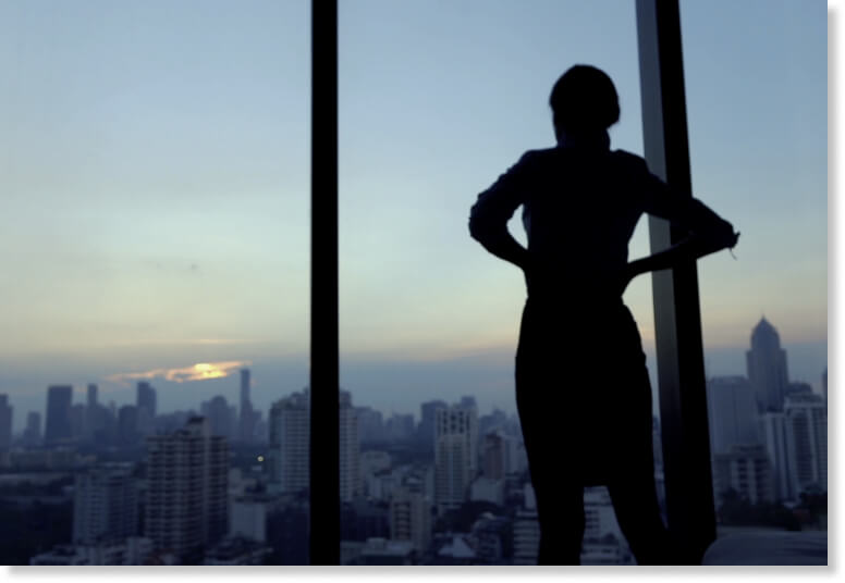 Person looking out of a tall building window.